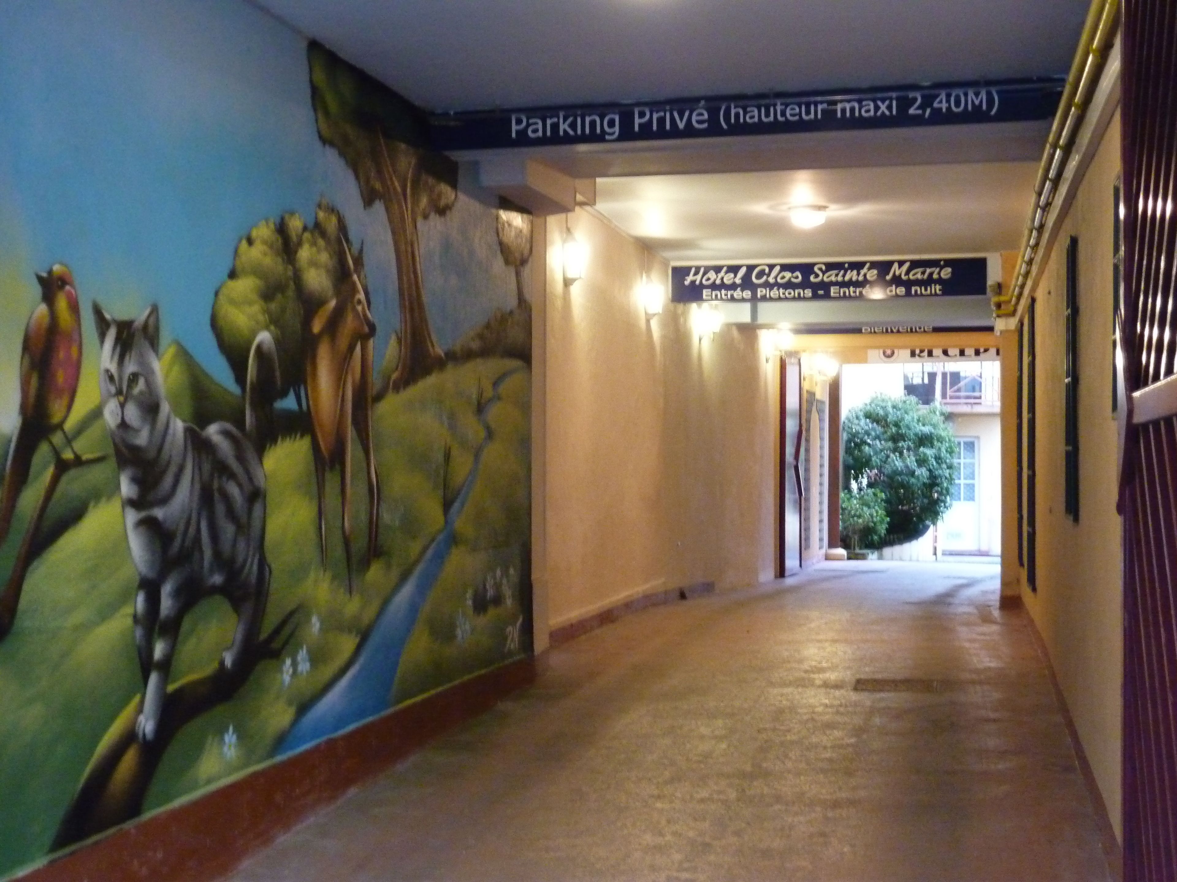 A hallway with a mural of animals and a sign for Hotel Clos Sainte Marie.