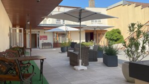 An outdoor patio area with seating, umbrellas, and potted plants. - The Originals Boutique, Hôtel Clos St Marie (Nevers)