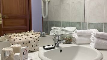 A bathroom with a sink, towel dispenser, and a wooden door.