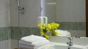 A bathroom with a sink, mirror, and a stack of white towels.