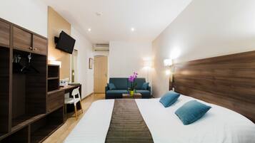 A hotel room with a bed, a desk, a wardrobe, a TV, and a sofa.