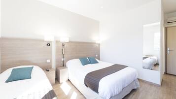 A hotel room with two beds, a wooden headboard, bedside lamps, and a mirror.