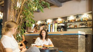 A bar area with wooden furniture and a variety of bottles on shelves. - Logis Hôtel Le Glacier (Orange)