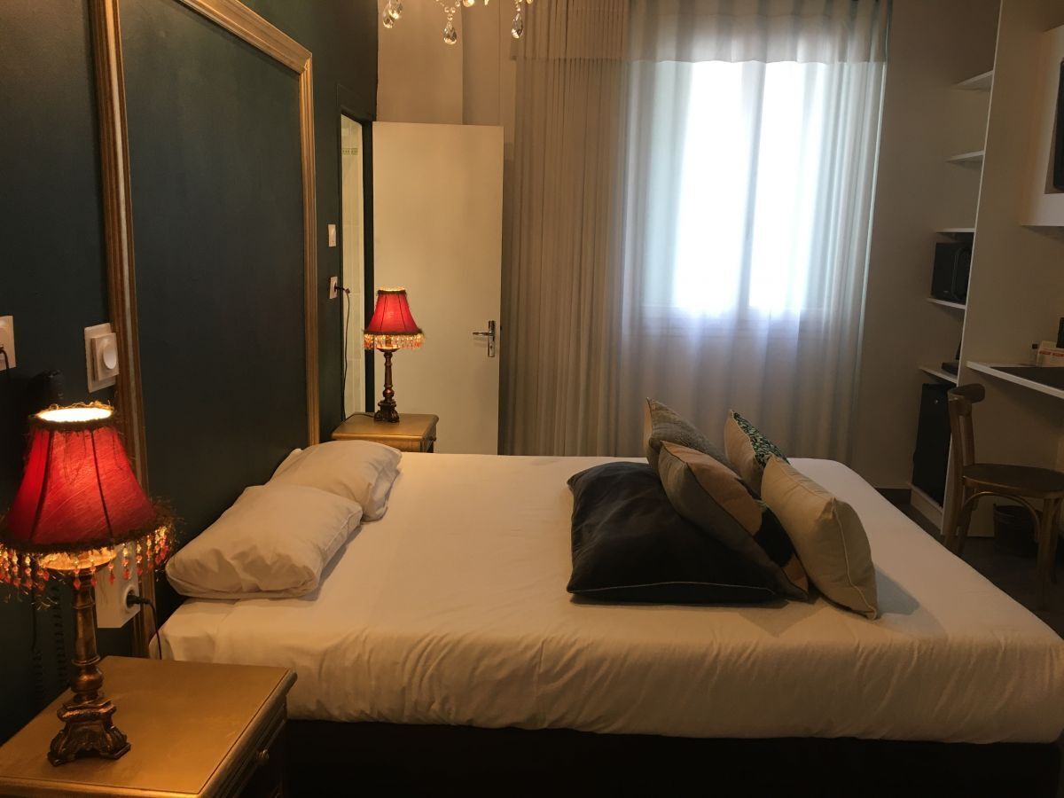 Una habitación de hotel con una cama grande, una lámpara de noche, un escritorio y una silla.