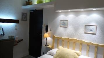 Un dormitorio con cama, lámpara de noche y un escritorio con silla.