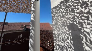 A building facade with a textured wall, a metal structure with a chain, and a clear blue sky. - Logis Hôtel Le Glacier (Orange)