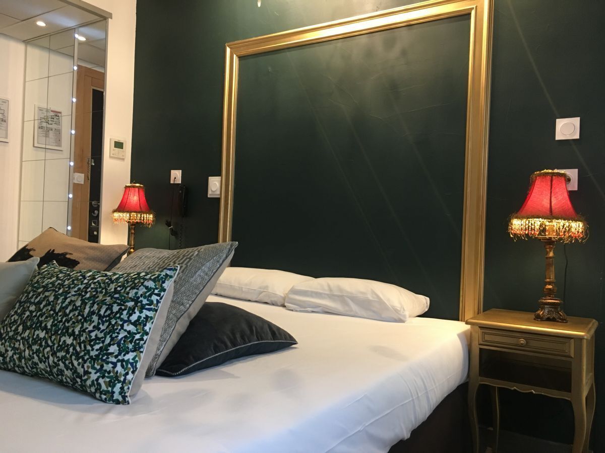 A hotel room with a large bed, two bedside lamps, and a mirror on the wall.