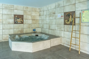 Zona de spa con hidromasaje, paredes de azulejos y señalización informativa.