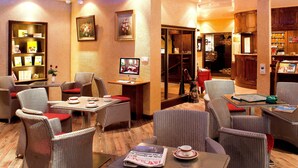 Un hall d’hôtel avec des meubles en osier, un comptoir d’accueil et un téléviseur.