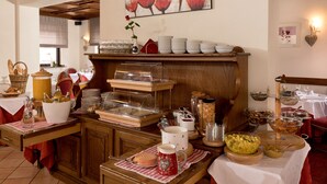 Un buffet de petit-déjeuner avec divers aliments et boissons, un buffet en bois et un tableau accroché au mur.