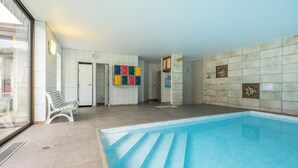 Une piscine dont le sol est carrelé et qui possède un banc près de l’entrée.