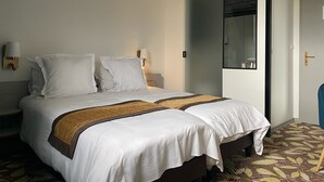 Un letto matrimoniale con lenzuola bianche e un tocco di colore marrone, un comodino con una lampada, uno specchio grande e un tappeto a motivi.