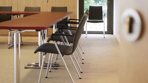 Una sala conferenze con un lungo tavolo, sedie e una porta con maniglia.