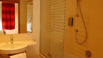 A bathroom with a sink, mirror, and shower.