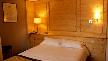 A hotel room with a large bed, wooden headboard, bedside lamps, a telephone, and a framed picture on the wall.
