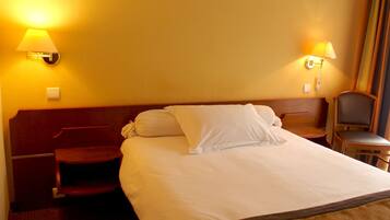 Una habitación de hotel con una cama grande, dos lámparas de noche, un cabecero de madera y una silla.