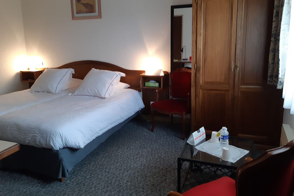A hotel room with a bed, a chair, a desk, and a wardrobe.