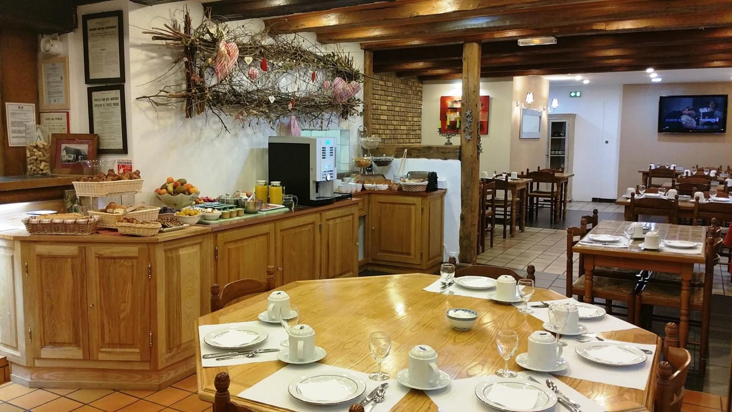 A restaurant with wooden furniture, a buffet counter, and a TV screen.