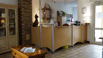 Un área de recepción con un escritorio de madera, una pared de ladrillo y una mesa de recepción con un cartel.