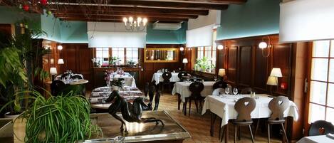 Un restaurante con varias mesas, sillas y una estatua decorativa de un caballo.