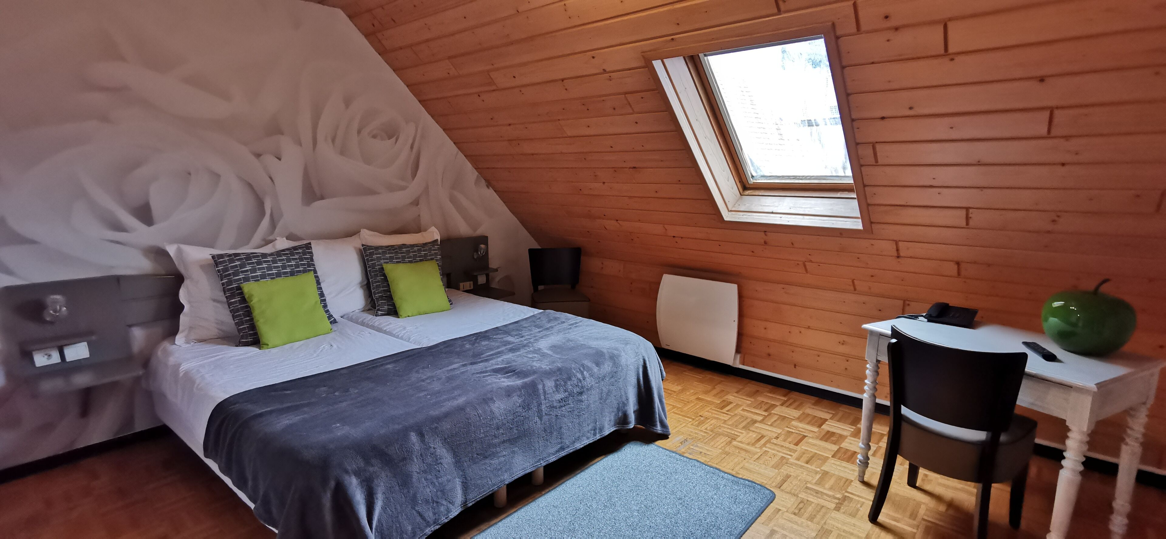 Quarto com cama, escrivaninha, cadeira, radiador e janela.