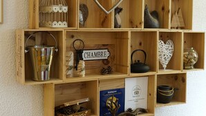 Une étagère en bois sur laquelle sont disposés divers objets, notamment un décor en forme de cœur, une horloge et une pancarte sur laquelle on peut lire « CHAMBRE ».