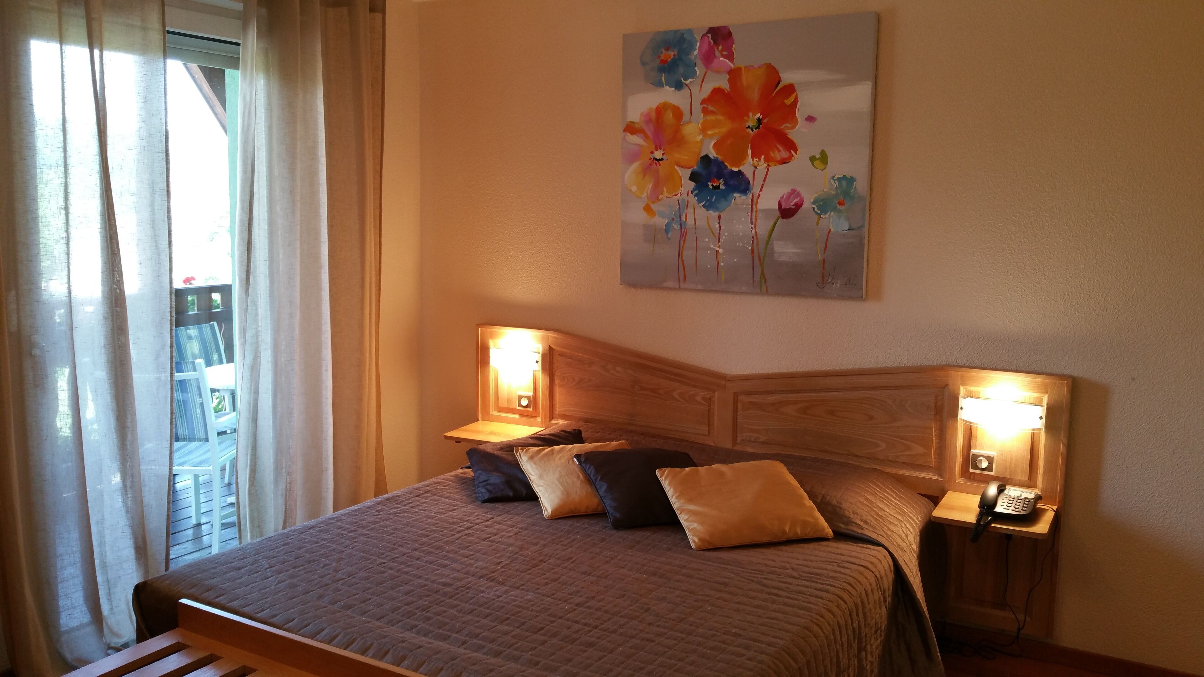 A bedroom with a bed, two bedside tables, a painting, and a window with curtains.