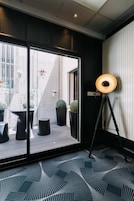 Een kamer met een groot raam, een vloerlamp en een kamer met een vloerkleed.