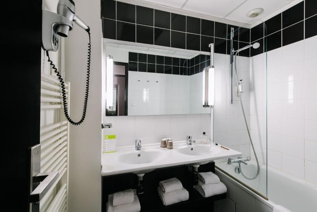 Une salle de bain moderne avec un grand miroir, deux lavabos, une douche et un téléphone.