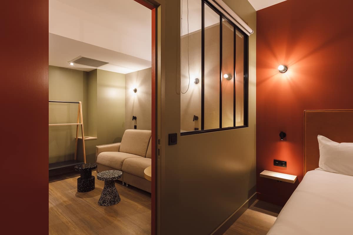 Ein Hotelzimmer mit Bett, Nachttisch, kleinem Tisch, Stuhl und Spiegel.