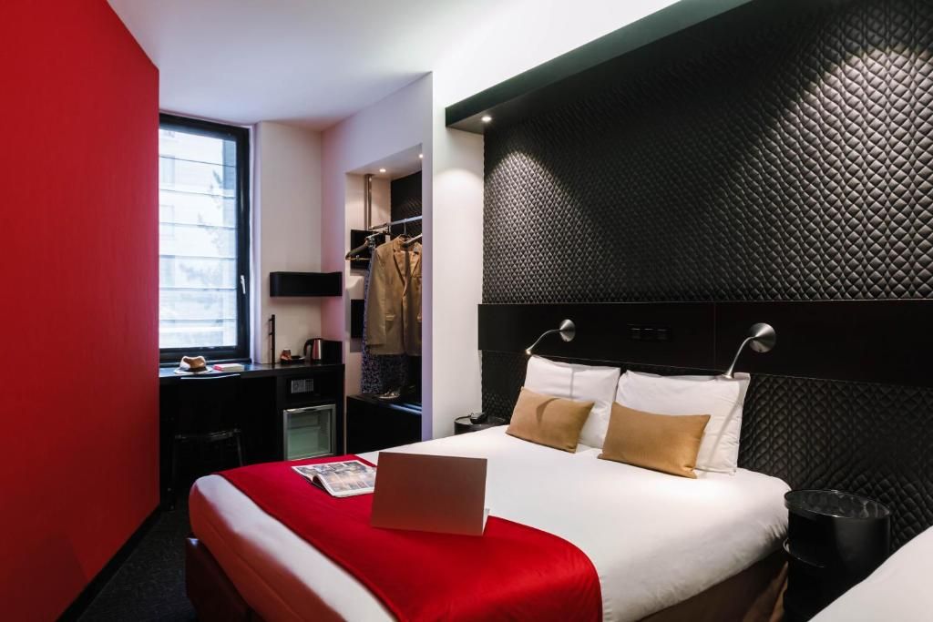 A hotel room with a bed, a desk, a wardrobe, and a window.