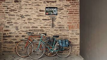 Un área de estacionamiento con dos bicicletas aparcadas junto a un muro de ladrillo. Un cartel encima indica 'RESERVE M2 Garden'.