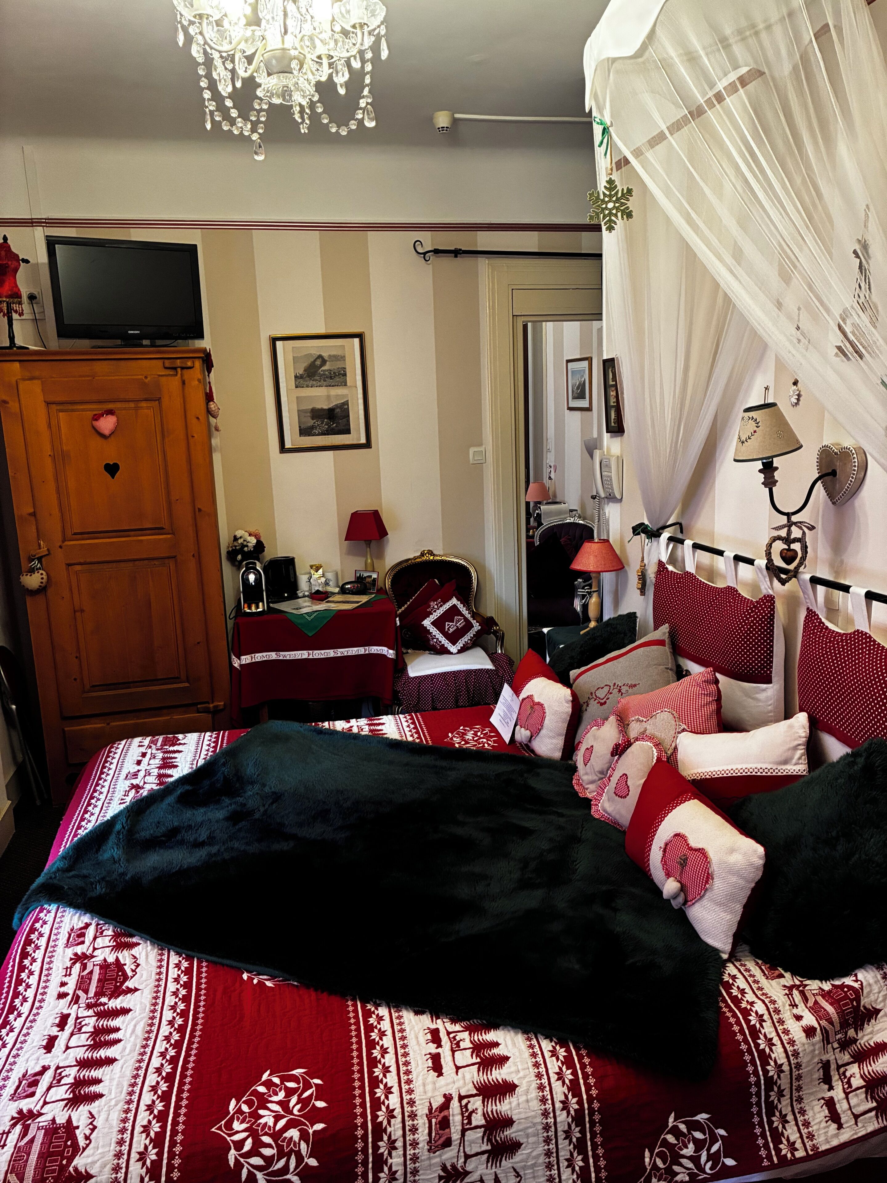 A bedroom with a bed, a television, a wardrobe, and a mirror.