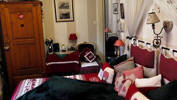 A bedroom with a bed, a television, a wardrobe, and a mirror.