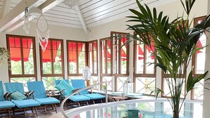 Un área de spa con un jacuzzi, sillones reclinables azules y una planta grande en maceta.
