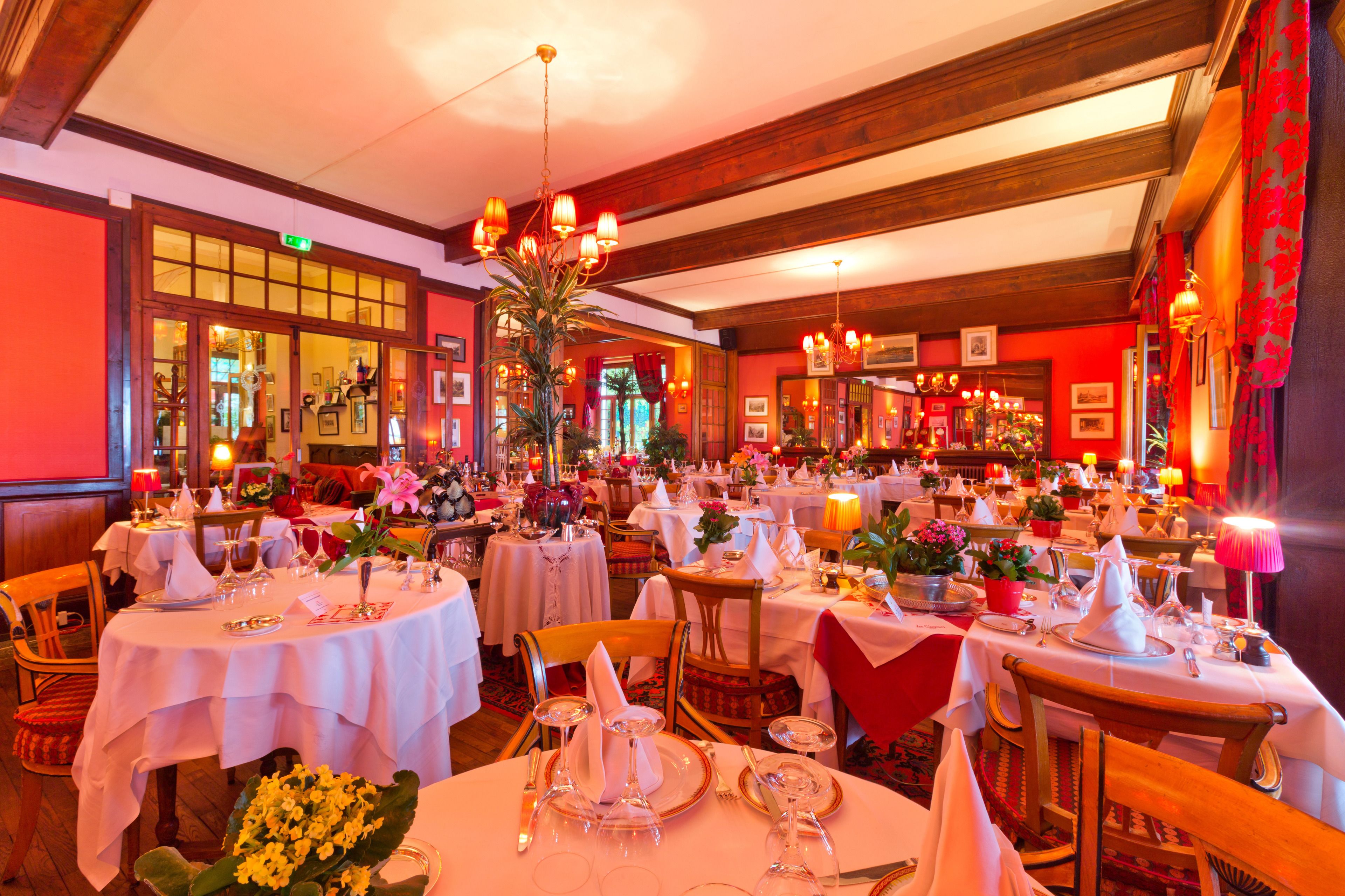 A restaurant with round tables set for dining, featuring white tablecloths and various centerpieces.