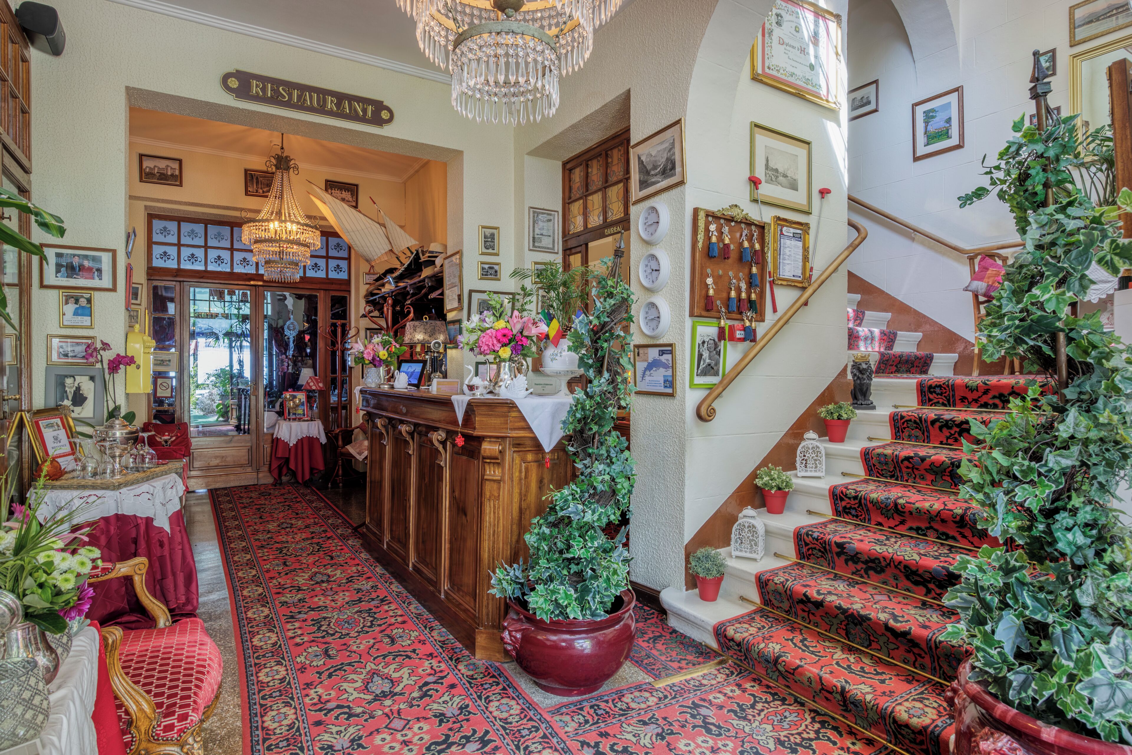 Un vestíbulo de hotel con una imponente escalera, una recepción y un candelabro.