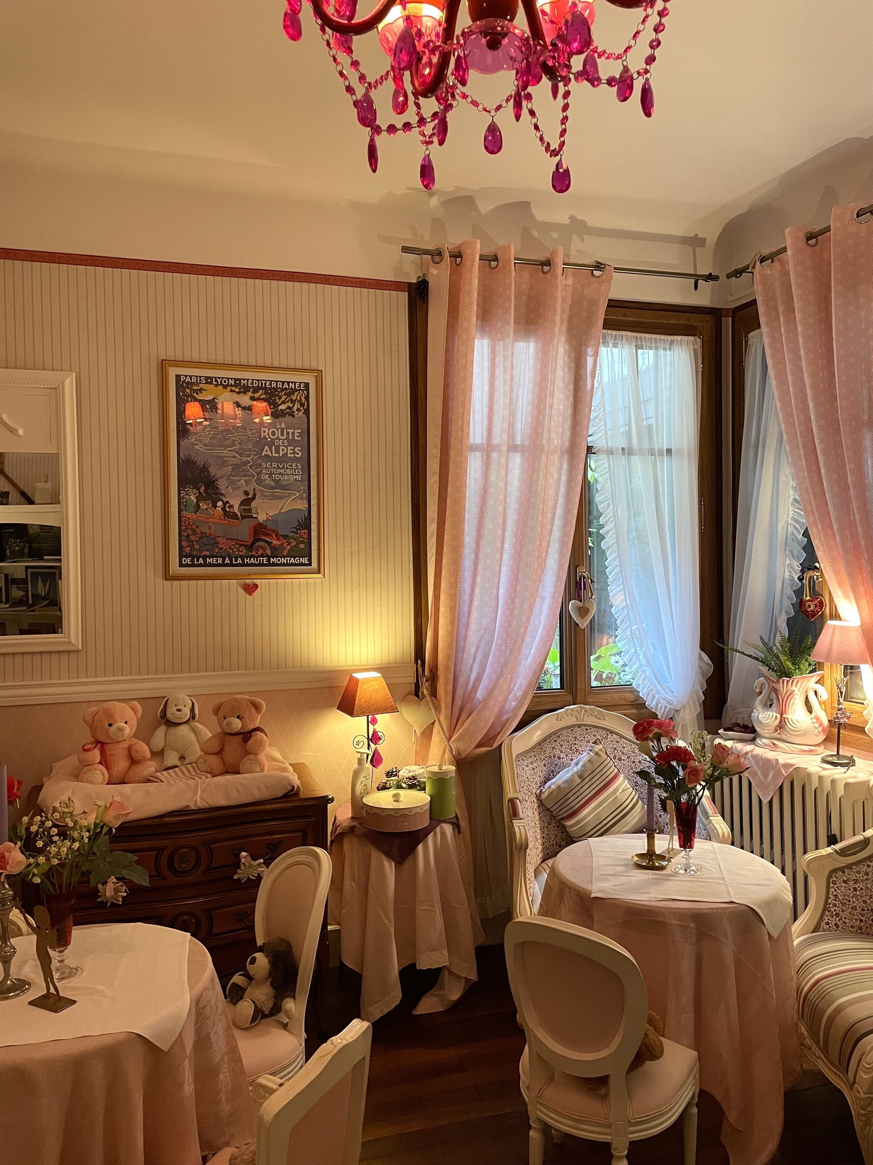 A cozy room with a bed, a small table with a lamp, a chair, and a window with curtains.