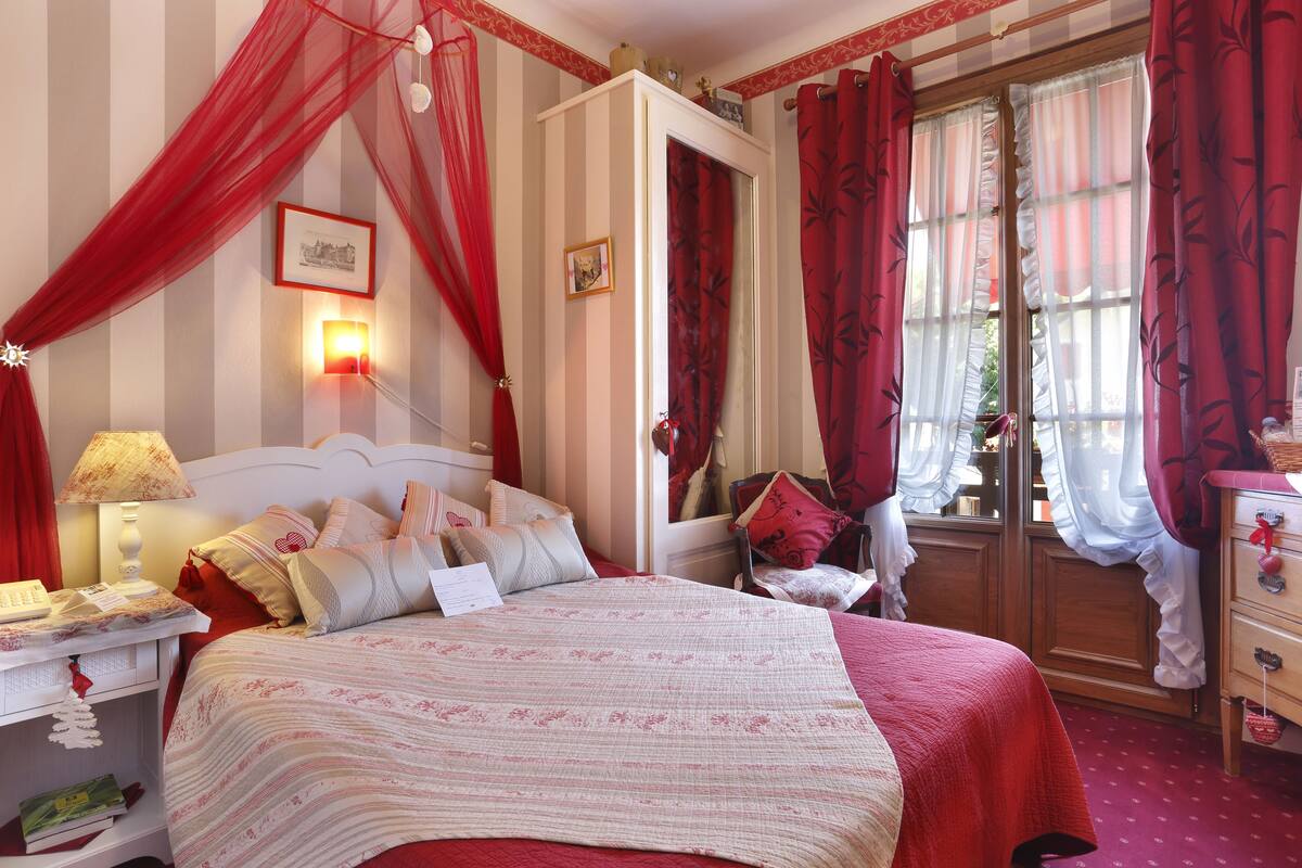 Un dormitorio con una cama grande, una mesita de noche, un armario y una ventana con cortinas.