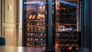 A wine cellar with rows of wine bottles, a door, and a table with chairs. - l'Abreuvoir (Heric)