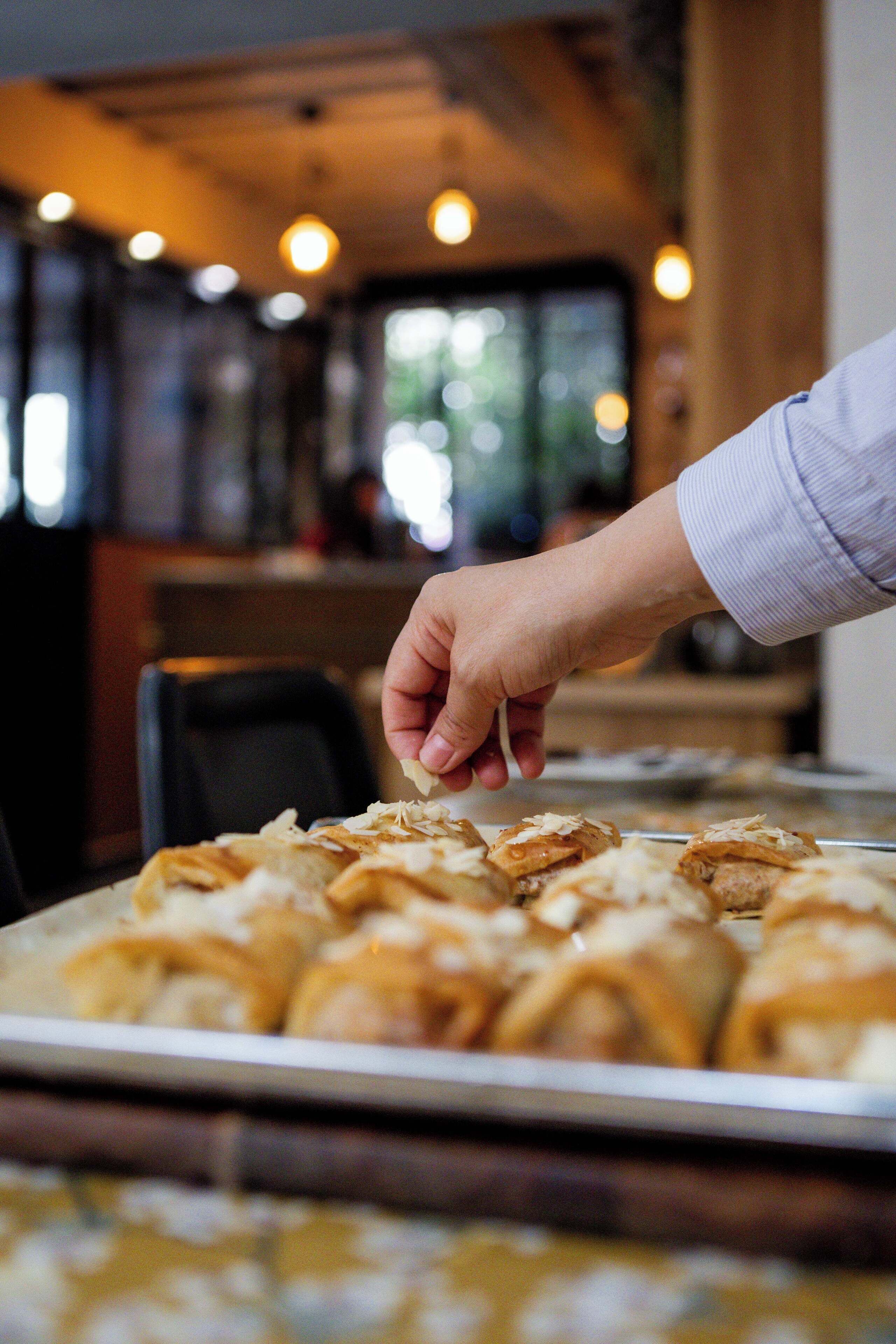 A hand reaching for pastries on a tray.
