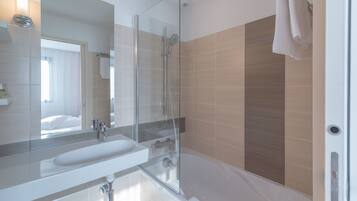 A modern bathroom with a glass-enclosed shower, a white sink, and a large mirror.