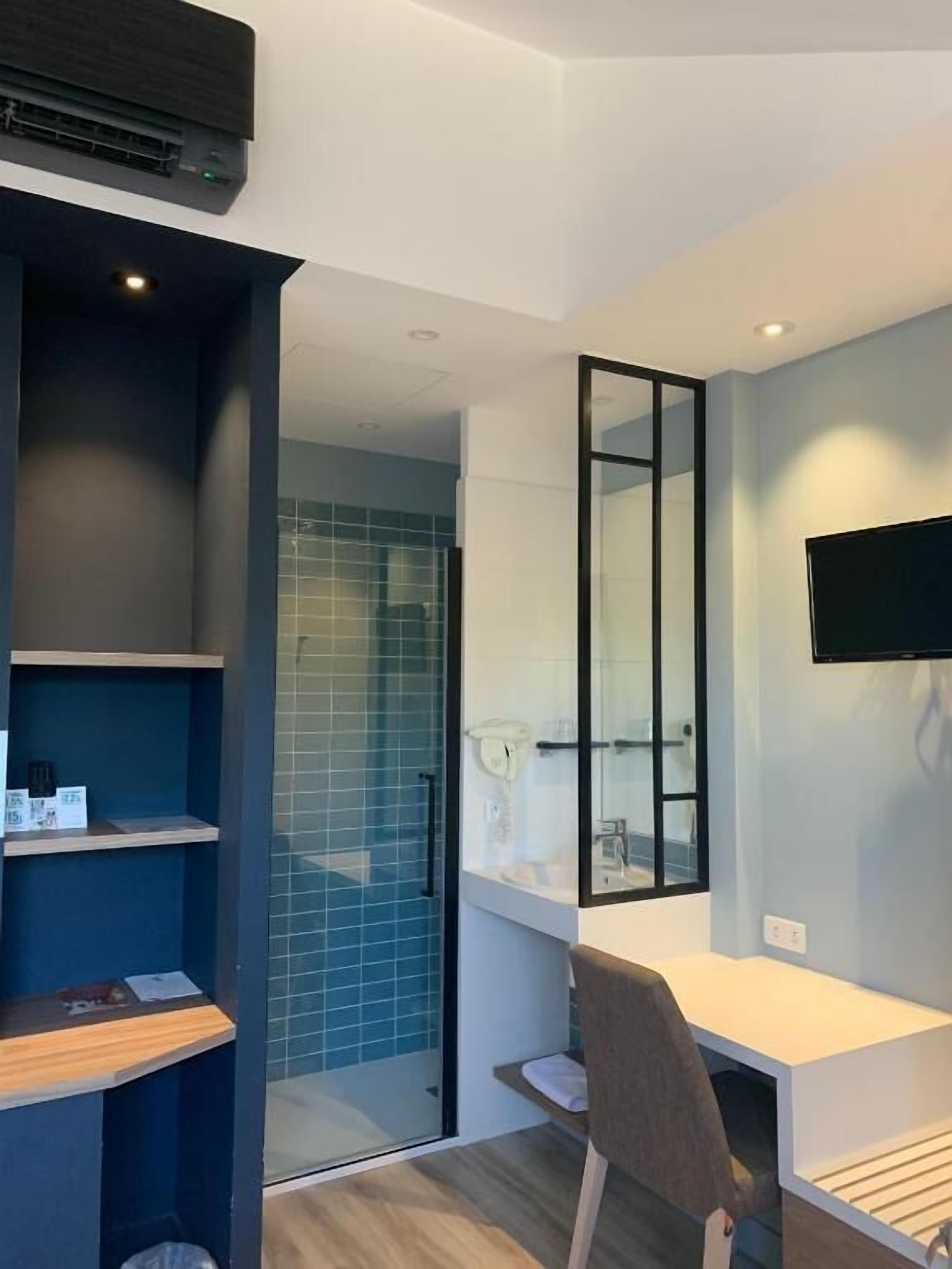 A modern bathroom with a shower, a mirror, a sink, and a television mounted on the wall.
