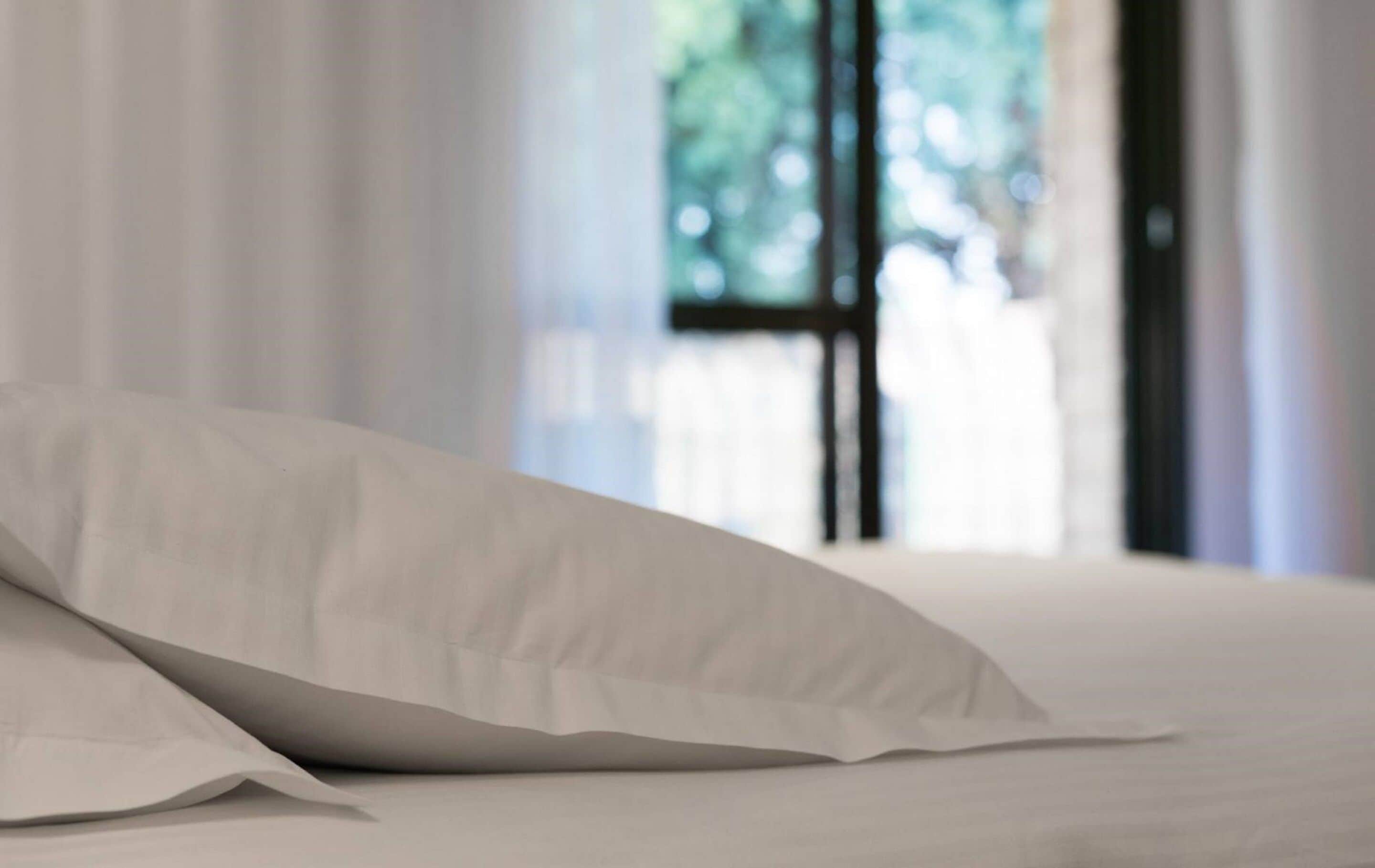 A bed with white bedding and a white pillow.