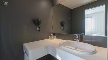 Une salle de bain moderne avec un lavabo blanc, des murs sombres et un grand miroir.