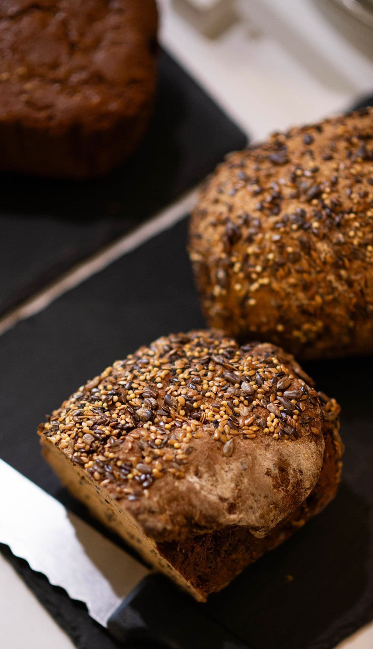 Ein Brot mit Saaten auf einer schwarzen Fläche.
