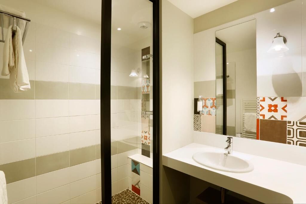 A modern bathroom with a glass shower enclosure, a white sink, and a large mirror.