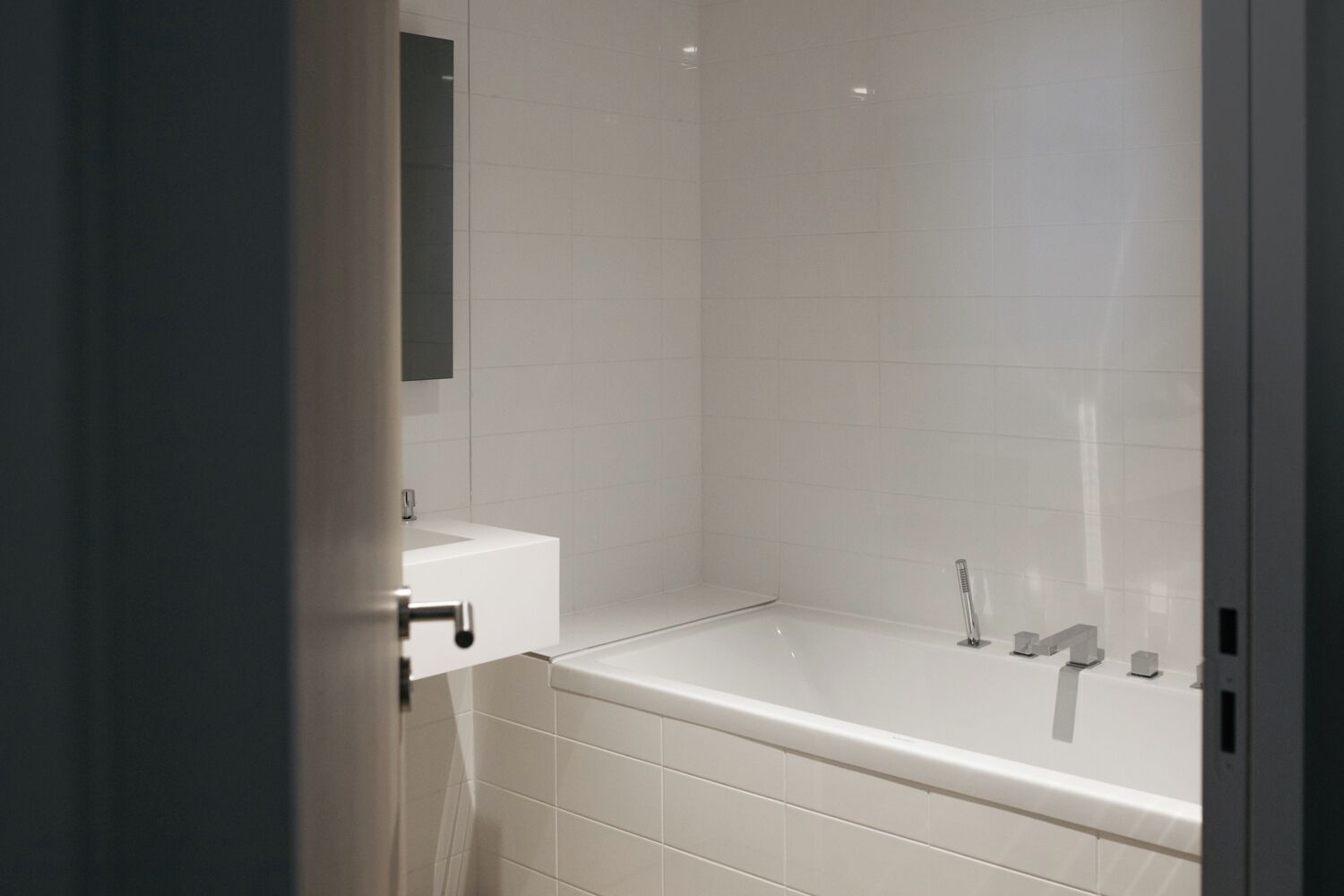 A modern bathroom with a white bathtub, a sink, and a mirror.