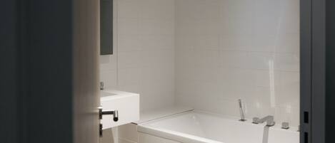 A modern bathroom with a white bathtub, a sink, and a mirror.