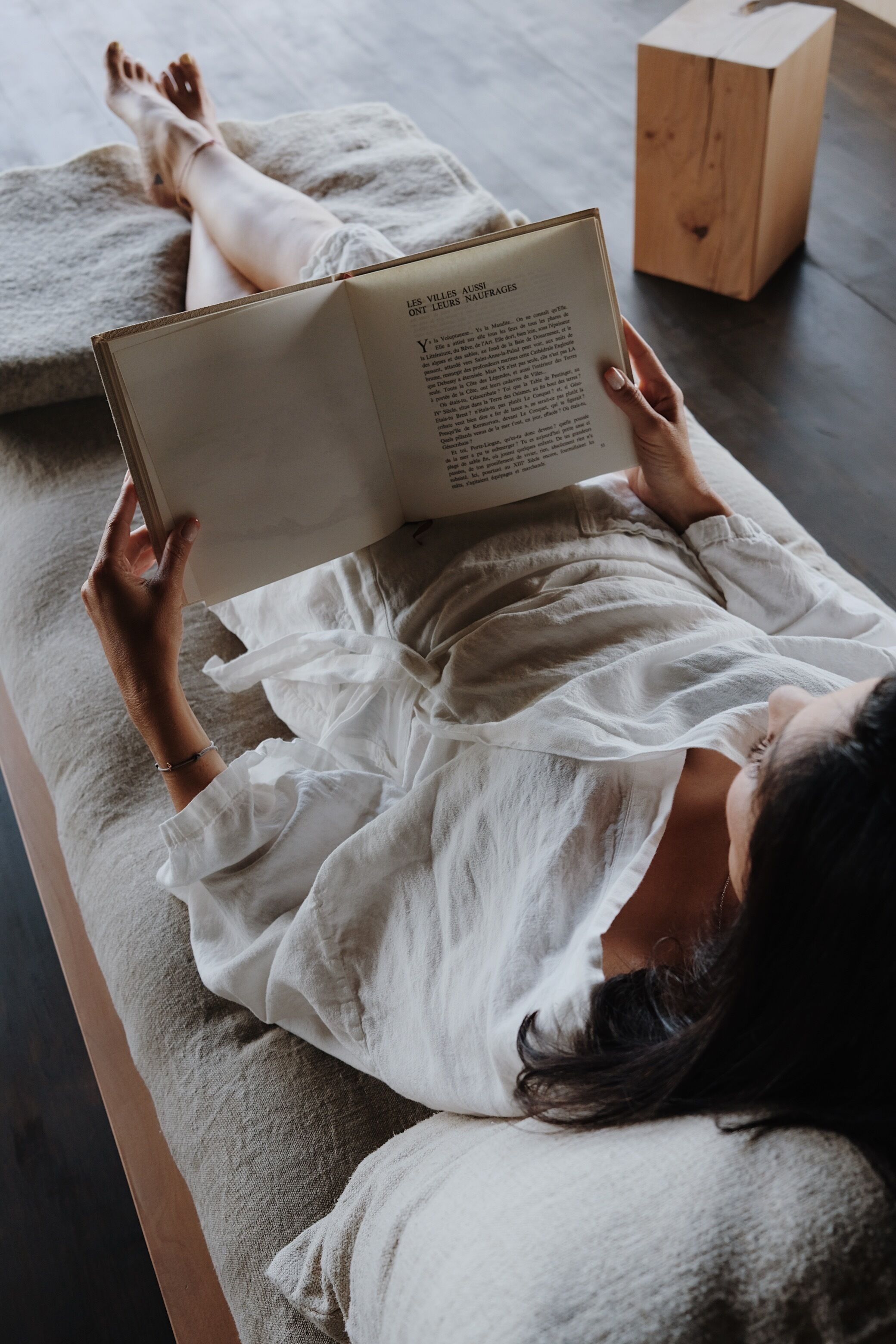 Una persona acostada en una cama leyendo un libro.